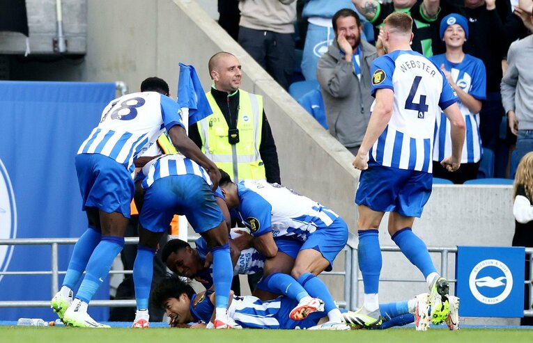 途中出場からわずか15秒でのゴール【4枚目／全4枚】。三笘のもとへ、折り重なるブライトンの選手たち。このとき顔にラインの石灰がついたようだ（冒頭の写真参照）　©AFLO