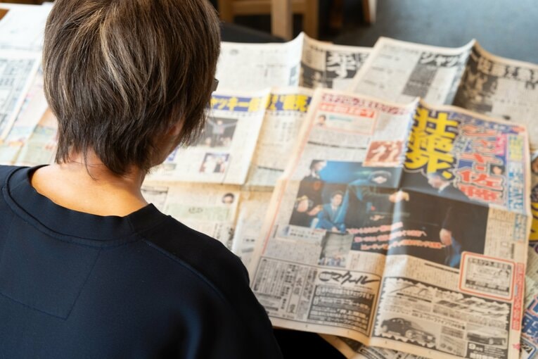 ジャッキー佐藤の死去を報じる当時の新聞を読むマキ上田　©Shiro Miyake
