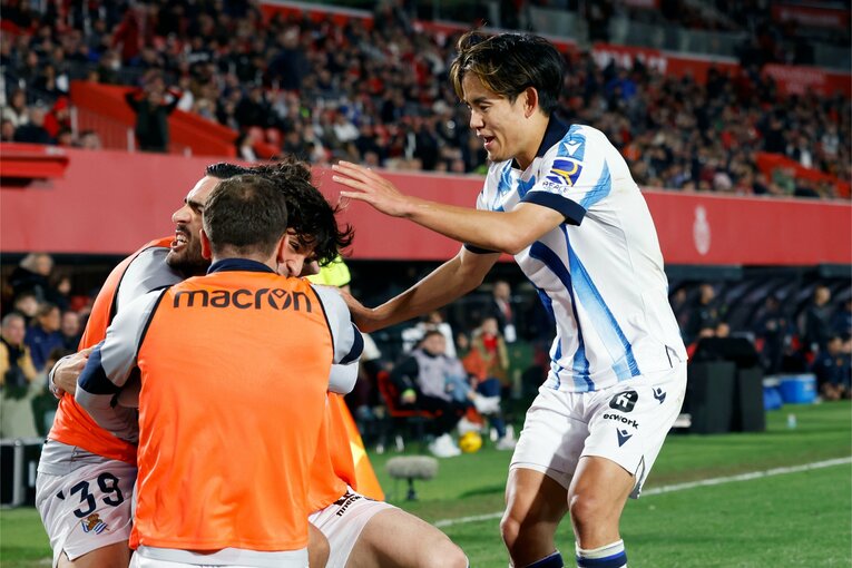 喜ぶメリノと仲間たちを笑顔で称える久保