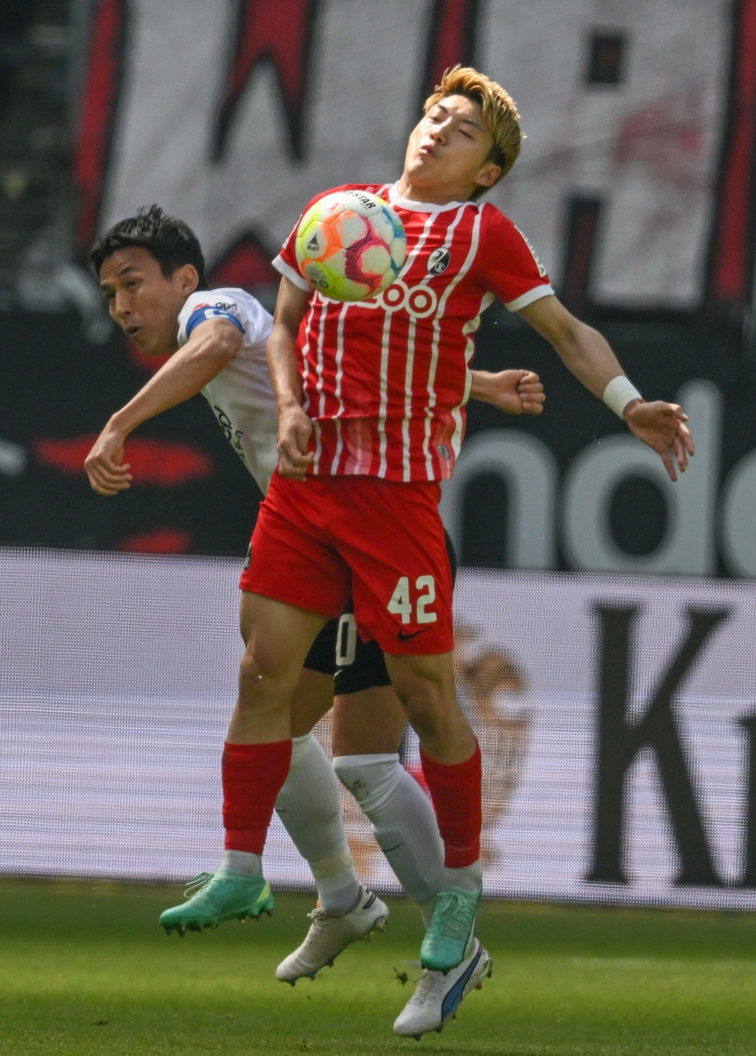 フライブルク戦、堂安と競り合う長谷部　©JIJI PRESS