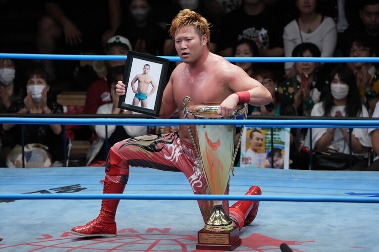 長尾一大心選手の遺影と優勝トロフィーで写真撮影に応じる宮原健斗　©Essei Hara