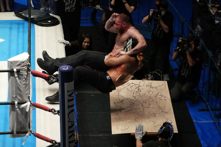 有刺鉄線ボードへの捨て身のバックドロップ（クリックすると「この記事の写真」に飛びます。流血等の過激な写真を含みますのでご注意ください）