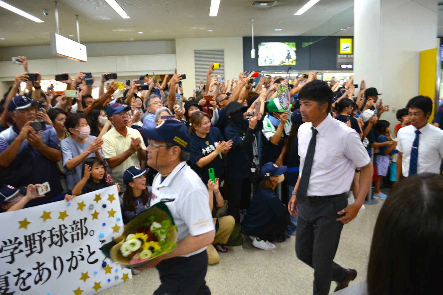 熱烈な出迎えを受けても表情を崩さない比嘉公也監督　©Takarin Matsunaga