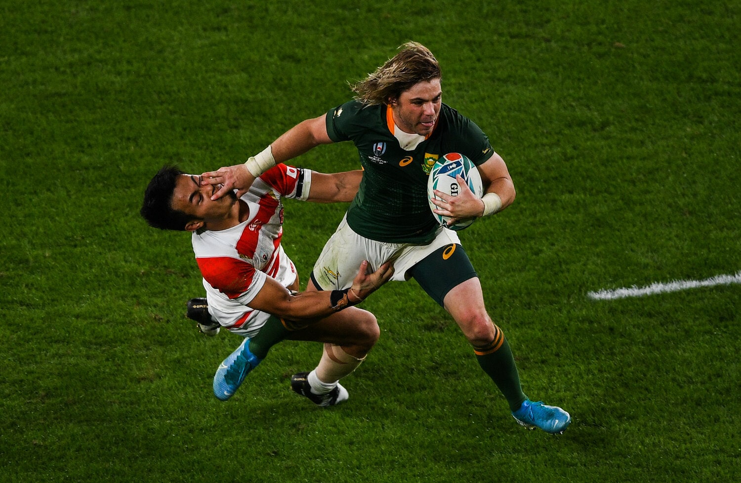 追いすがる福岡堅樹（左）に強烈なハンドオフを見舞い、日本からトライを奪ったデクラーク　©︎Getty Images