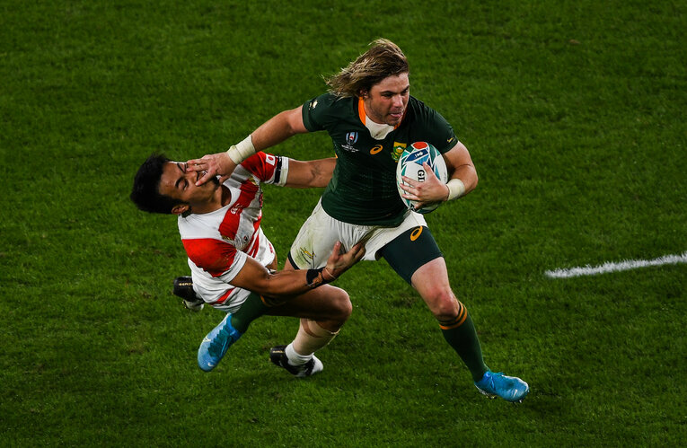 追いすがる福岡堅樹（左）に強烈なハンドオフを見舞い、日本からトライを奪ったデクラーク　©︎Getty Images