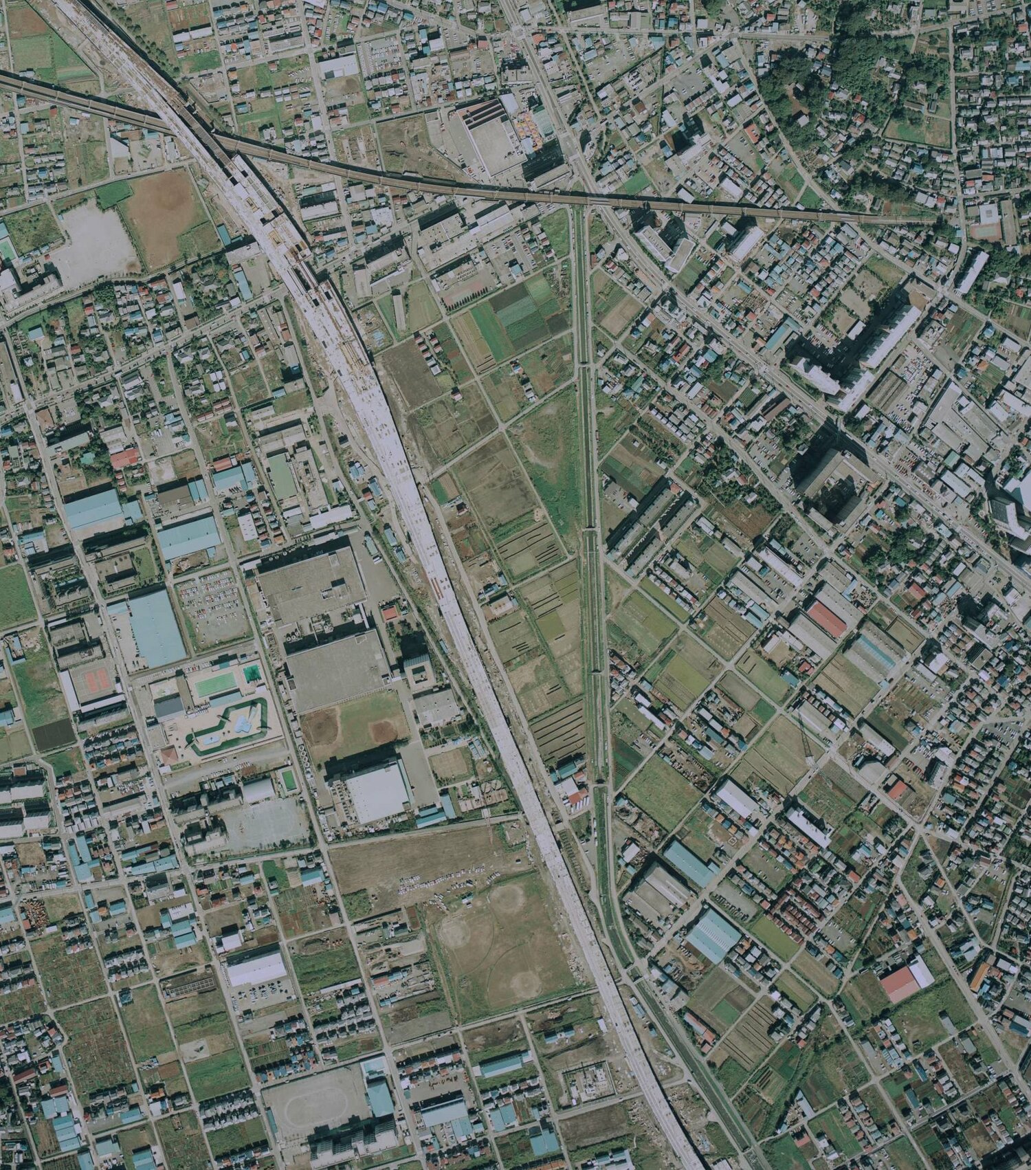 1984年に撮影された武蔵浦和付近の航空写真。中央左、大きな四角が3つ並ぶのがロッテ浦和工場。翌85年に埼京線が開業するが、写真左上~右下へ線路工事が進んでいることが分かる 出典:国土地理院の空中写真