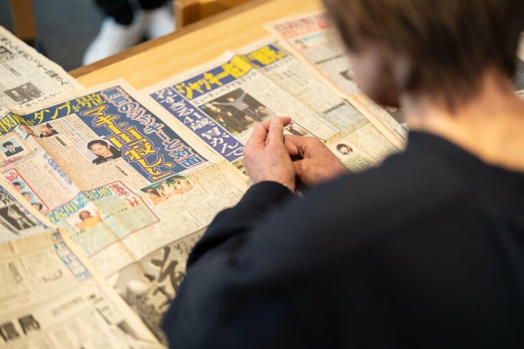 ジャッキー佐藤の死去を報じる当時の新聞を読むマキ上田　©Shiro Miyake