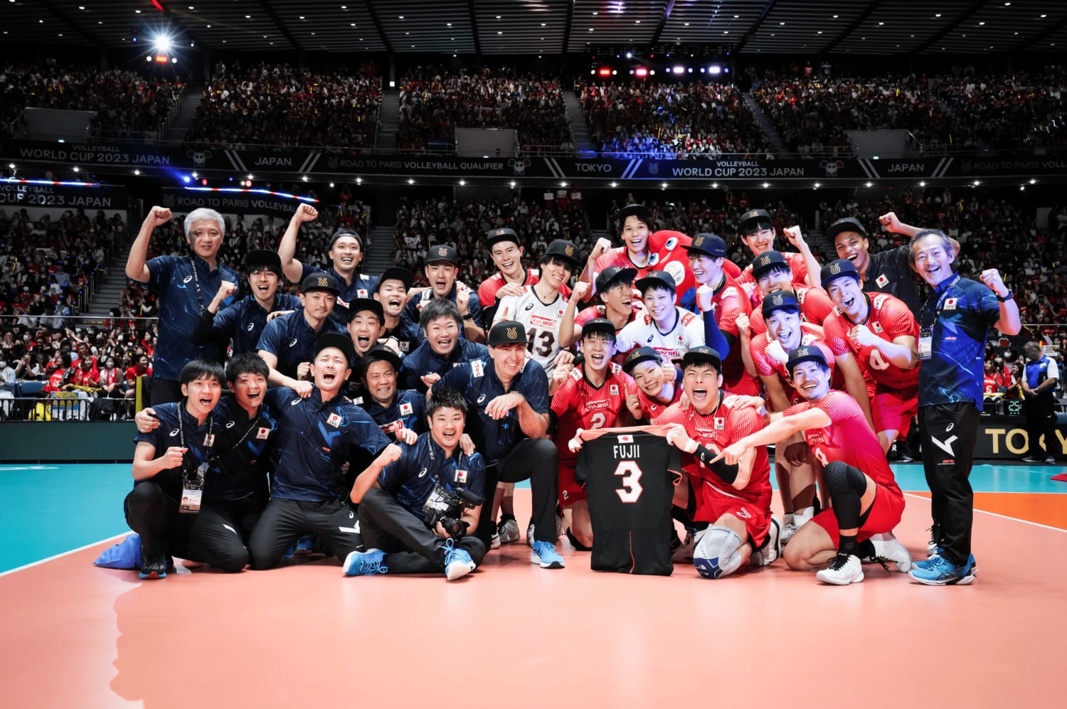 今年3月に亡くなった藤井さんのユニフォームと共に記念撮影する日本代表。実にブラン監督も嬉しそうだ　©︎FIVB