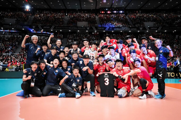 今年3月に亡くなった藤井さんのユニフォームと共に記念撮影する日本代表。実にブラン監督も嬉しそうだ　©︎FIVB