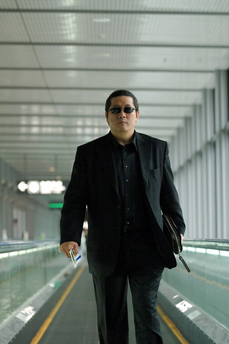 サングラスをかけて成田空港を歩く前田日明（2005年）　©Takashi Shimizu