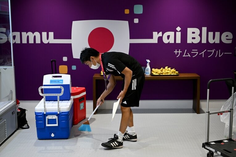 箒とちりとりを使って清掃するスタッフ（写真は2022年カタール大会）　©Getty Images