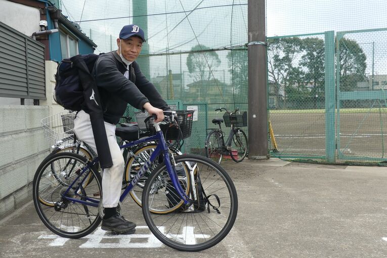 愛用の自転車で都心のグラウンドを行き来する山下さん。助っ人業で顔も広くなり、この日も隣のグラウンドの顔見知りと挨拶を交わしていた