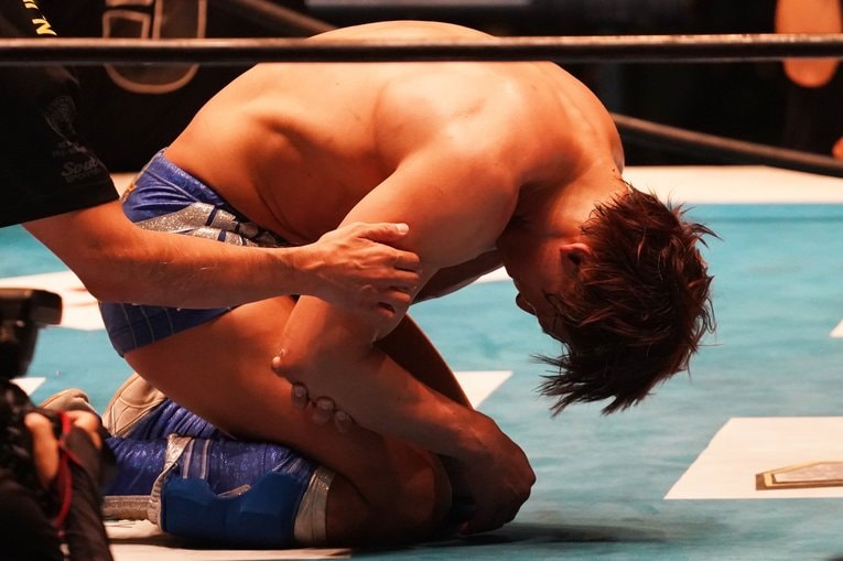 右腕を押さえてうずくまる飯伏。今年7月の誤嚥性肺炎につづくアクシデントとなってしまった