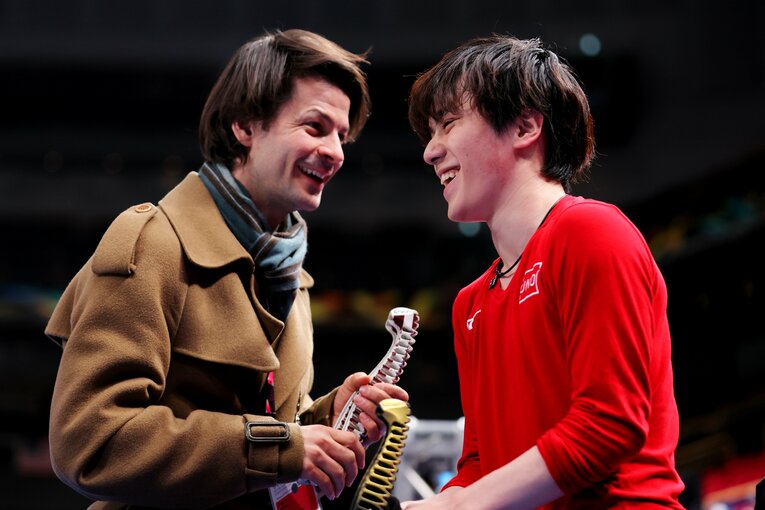 公式練習後に宇野に笑顔で話しかけるステファン・ランビエルコーチ　©︎AFLO