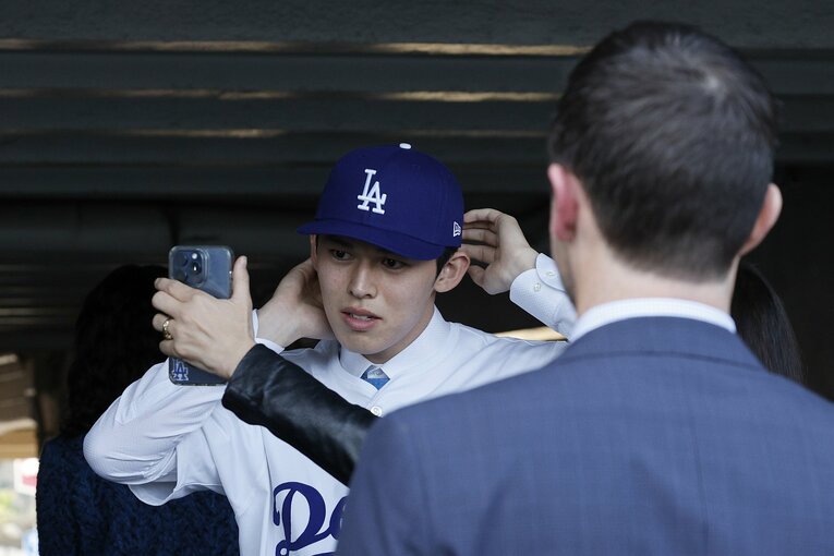 入団会見でドジャースの帽子を被る佐々木朗希　©︎Getty Images