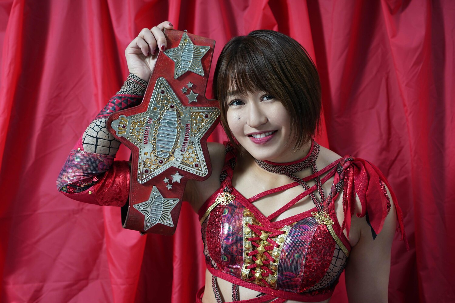 「女子プロレス大賞」を受賞し、赤いベルトを誇らしげに掲げる