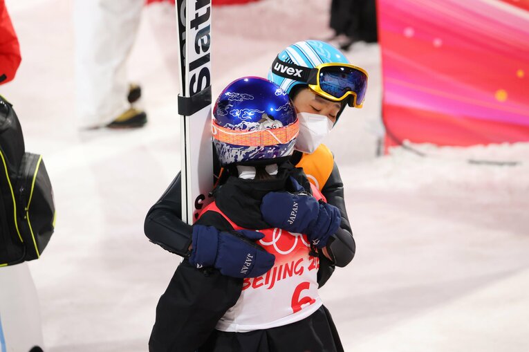 北京五輪混合団体でスーツ規定違反による失格となり、呆然とする高梨を抱きしめる伊藤　©AFLO