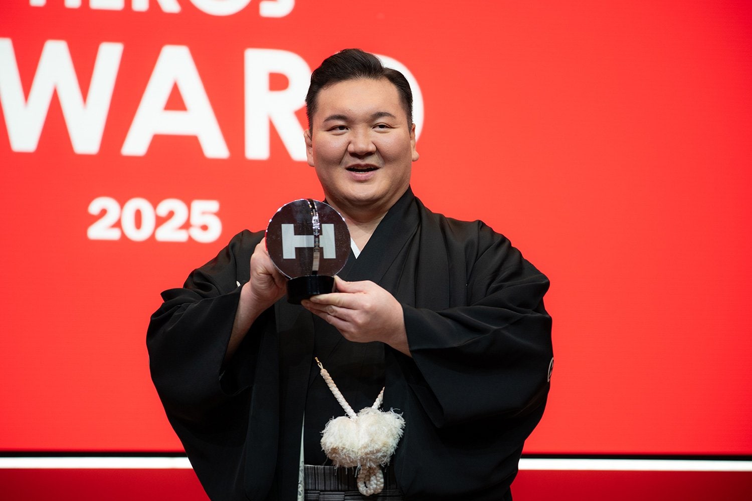 トロフィーを掲げる白鵬翔さん。2010年から実施し続けている「白鵬杯」の活動が評価された