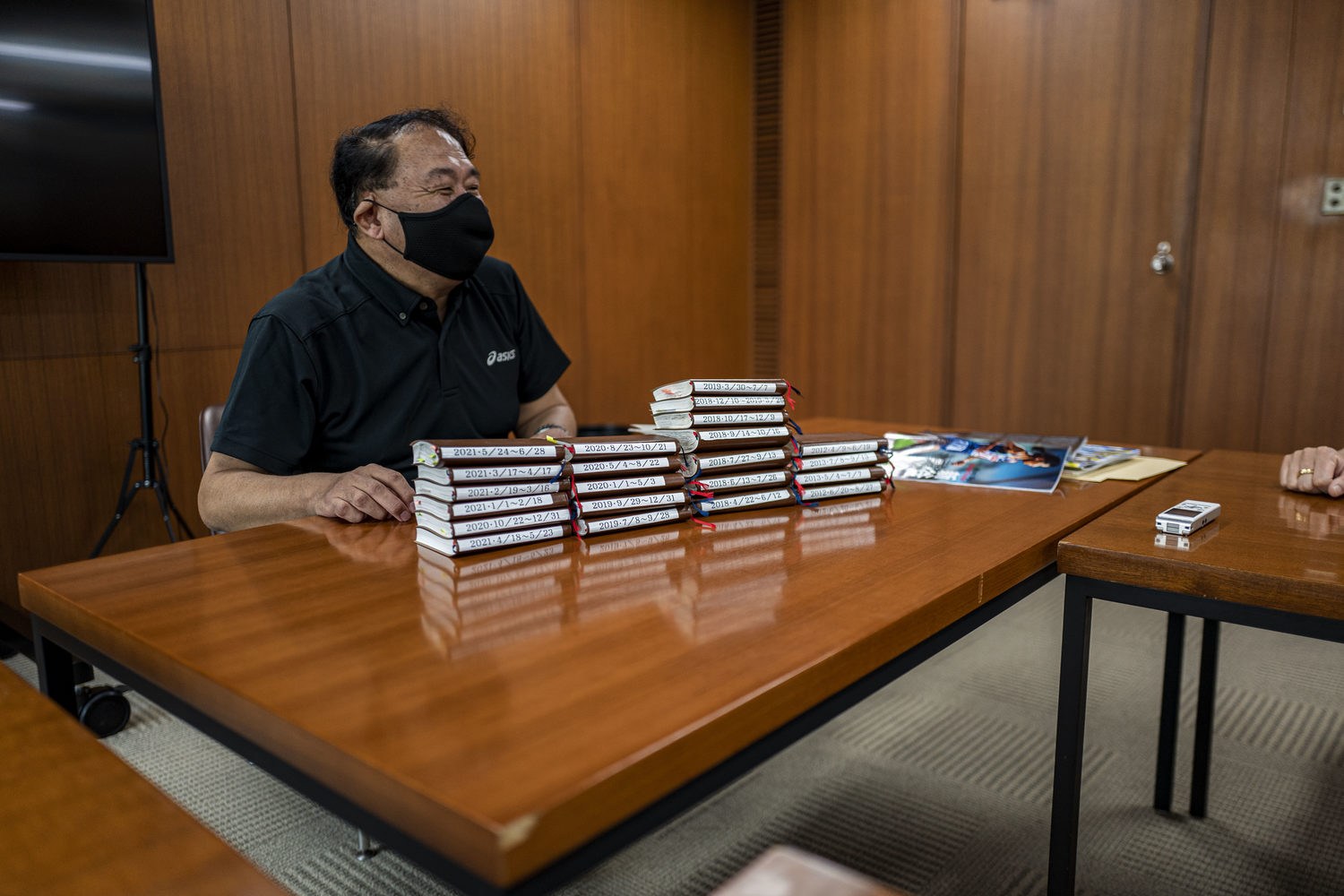 「マラソン博士」森岡芳彦さん。目の前に積まれているのが長距離選手のあらゆる記録をメモしている手帳　©Takeshi Nishimoto