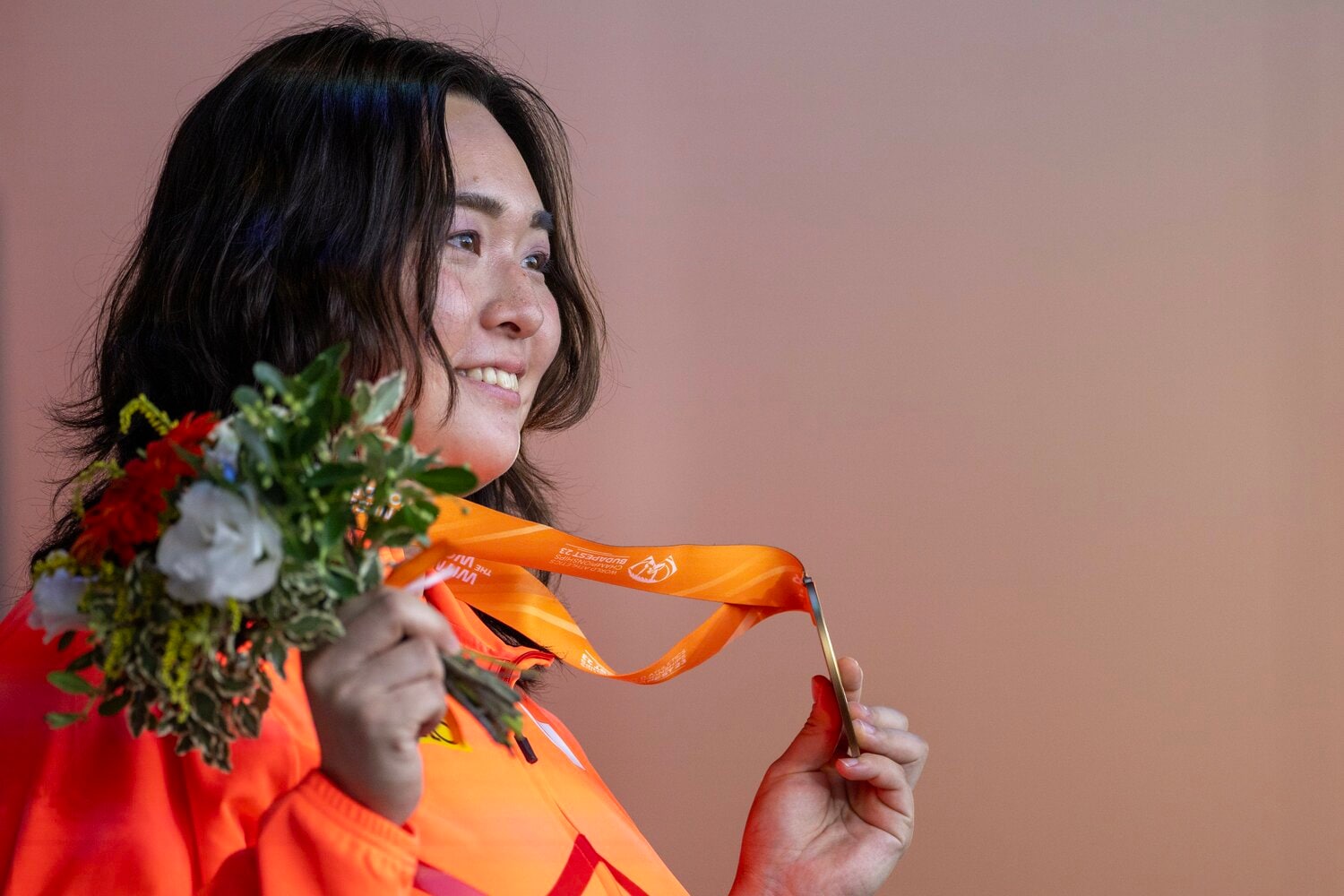 髪をおろしたスタイルで金メダルを掲げる北口　©︎Getty Images