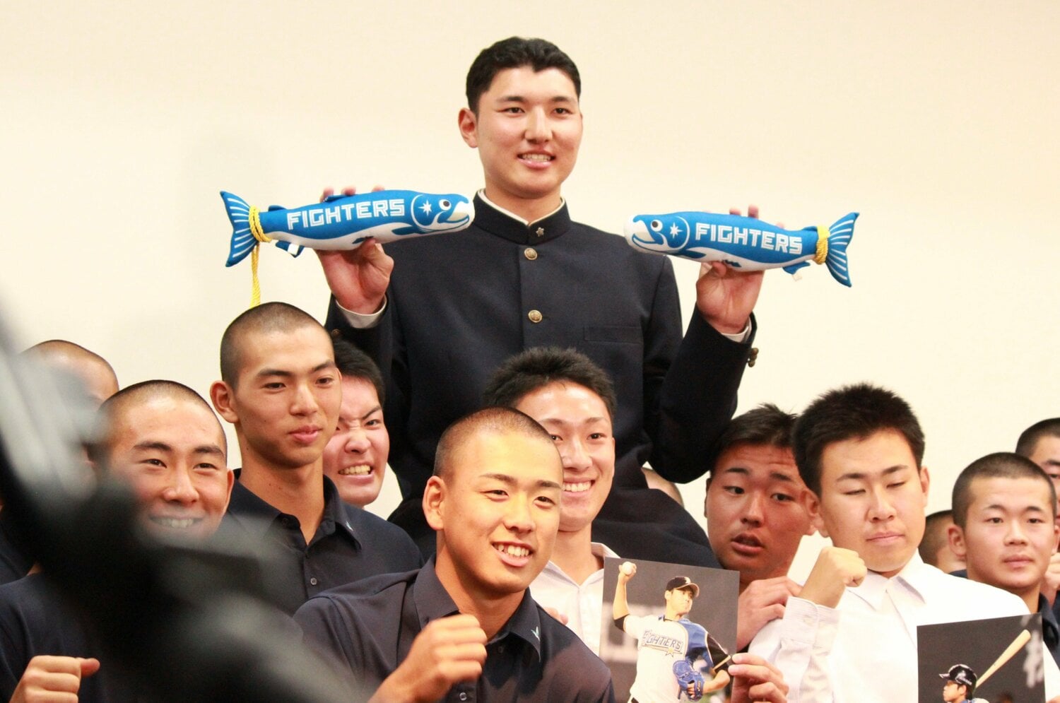 仲間に担がれ、日本ハムグッズの「しゃけまる」を手に記念撮影する菰田　©Yusuke Kondo