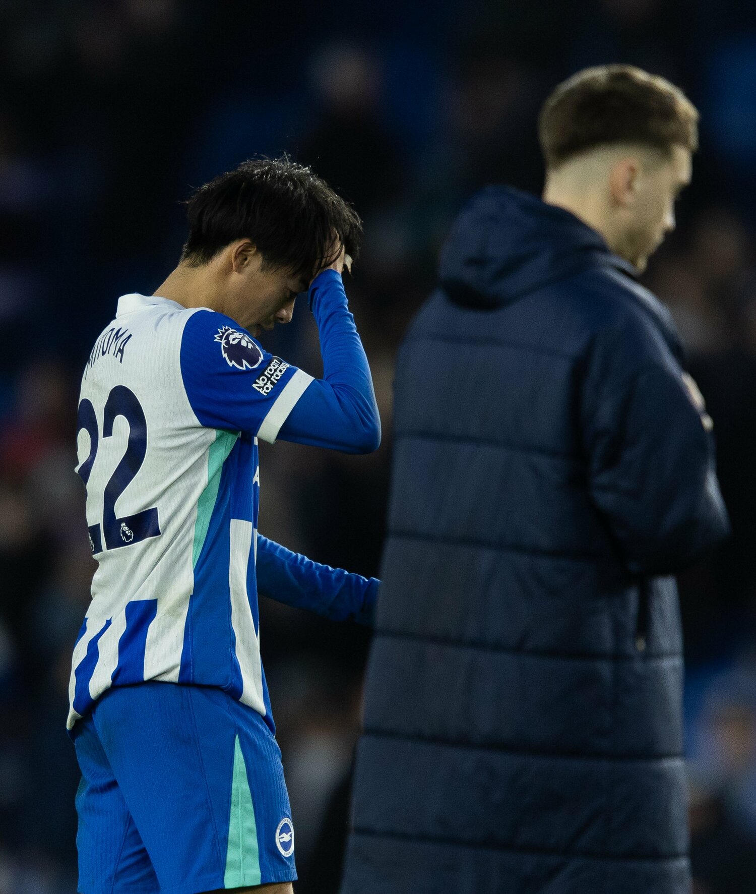 頭を抱え、落胆した表情でピッチを後にする三笘　©Getty Images