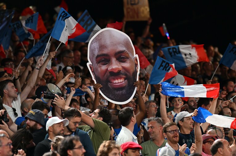 最近欧米のスポーツ現場でよく見かける「巨顔パネル」を振って応援するフランスの大観衆。後ろの人は見えるのだろうか ／ photograph by Naoya Sanuki/JMPA