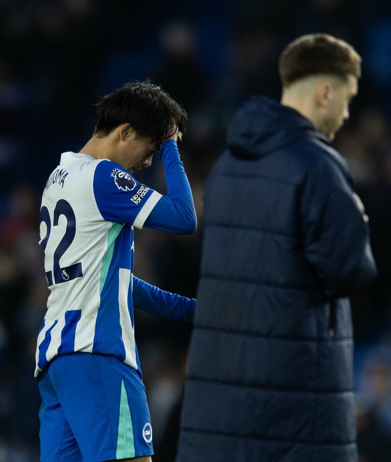 頭を抱え、落胆した表情でピッチを後にする三笘　©Getty Images