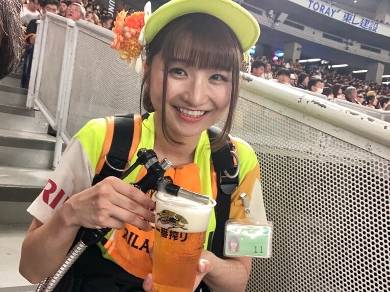 笑顔でビールを注ぐ仕事中の倉沢さん　©本人提供