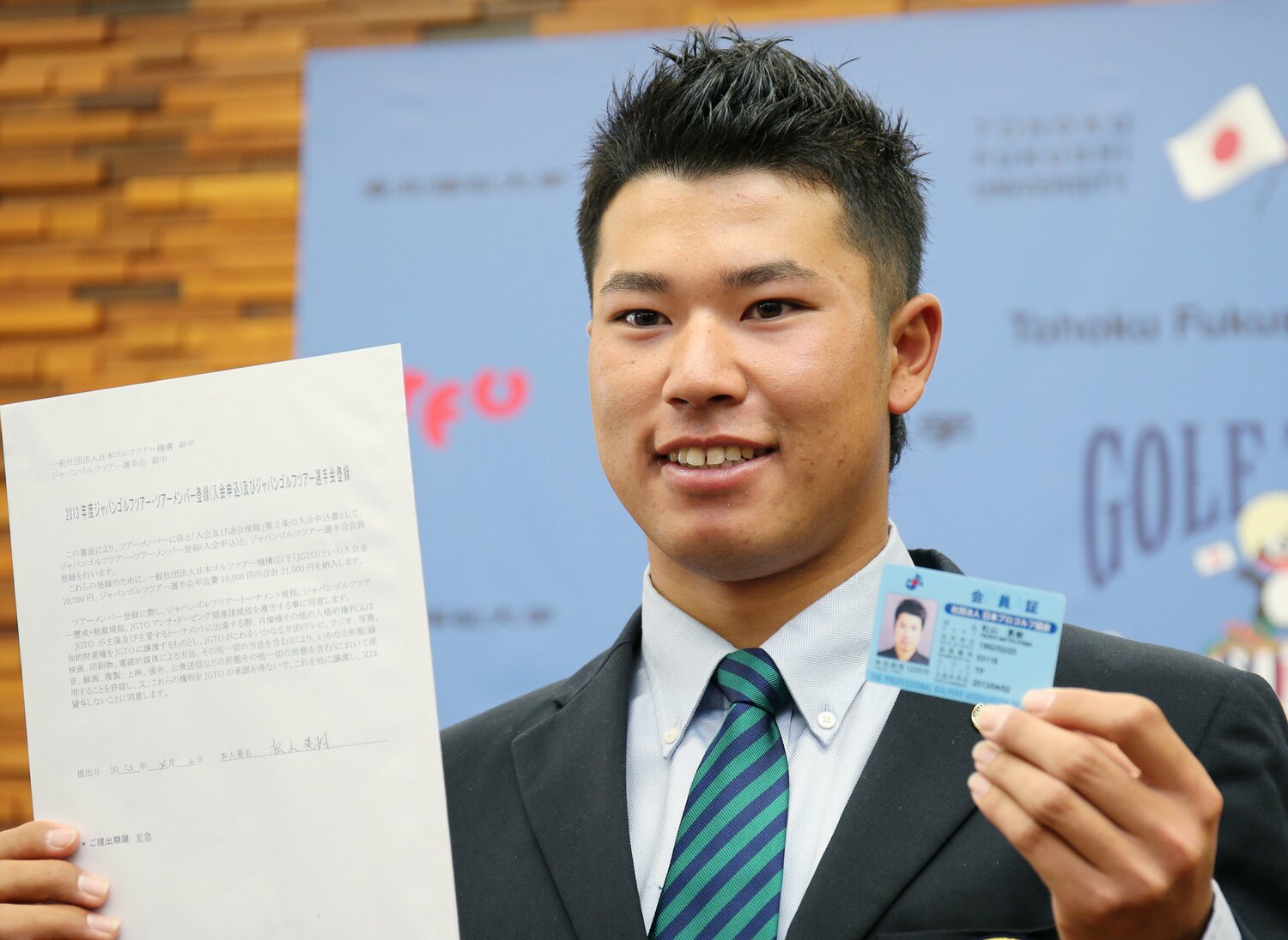 記者会見でプロ転向を宣言し、日本プロゴルフ協会の会員証を手にする東北福祉大学の松山英樹（2013年4月2日）©︎JIJI PRESS