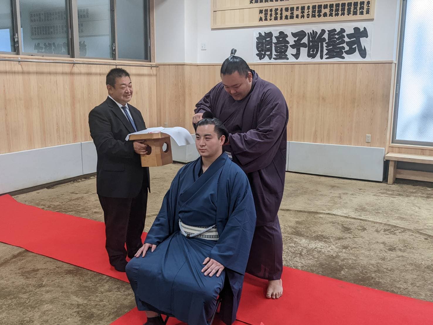 兄弟子・朝童子の断髪式。大銀杏にハサミを入れる朝乃山　©高砂部屋