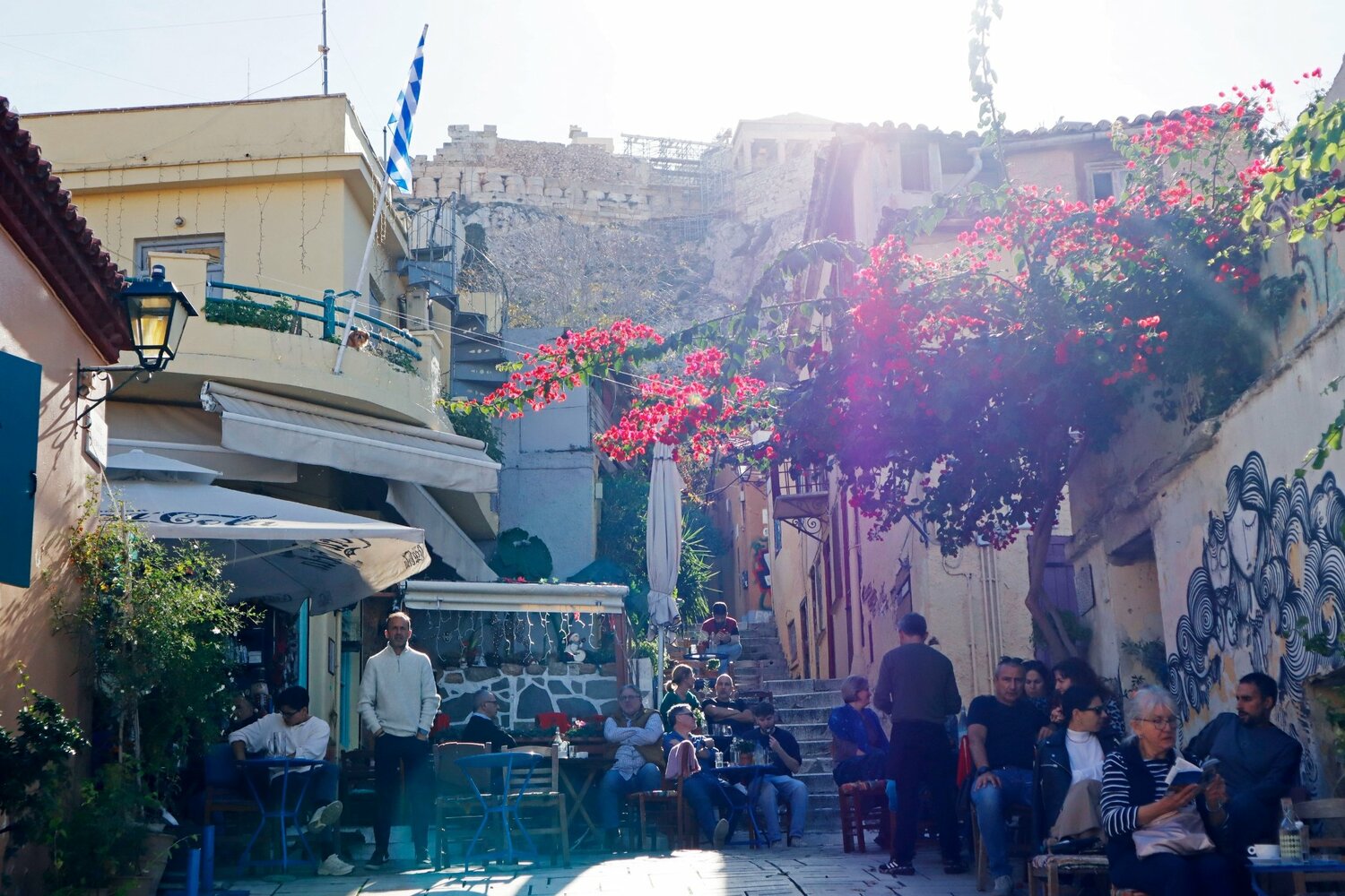 細い路地が入り組むプラカ地区のカフェ、頭上にはパルテノン神殿が