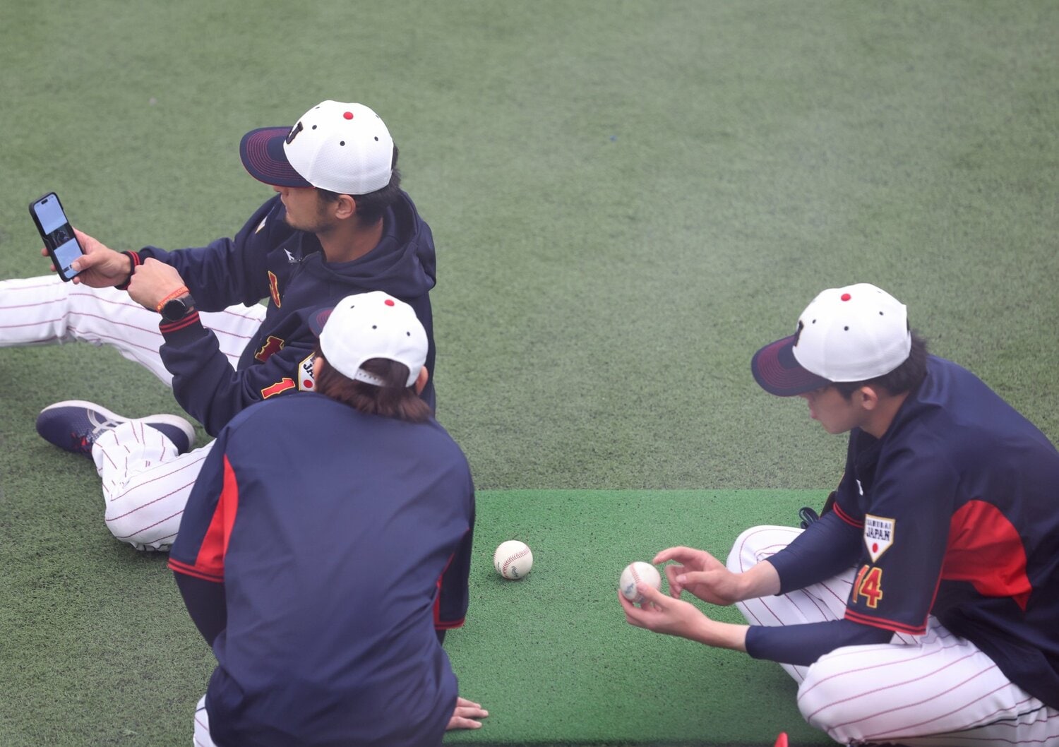宮崎合宿の初日、スマホで動画を見ながら野球談義をかわすダルビッシュ、佐々木、宮城©︎SANKEI SHIMBUN