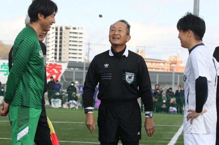 笑顔で22年ぶりのコイントスを行う主審・青木隆さん ／ photograph by Takahito Ando