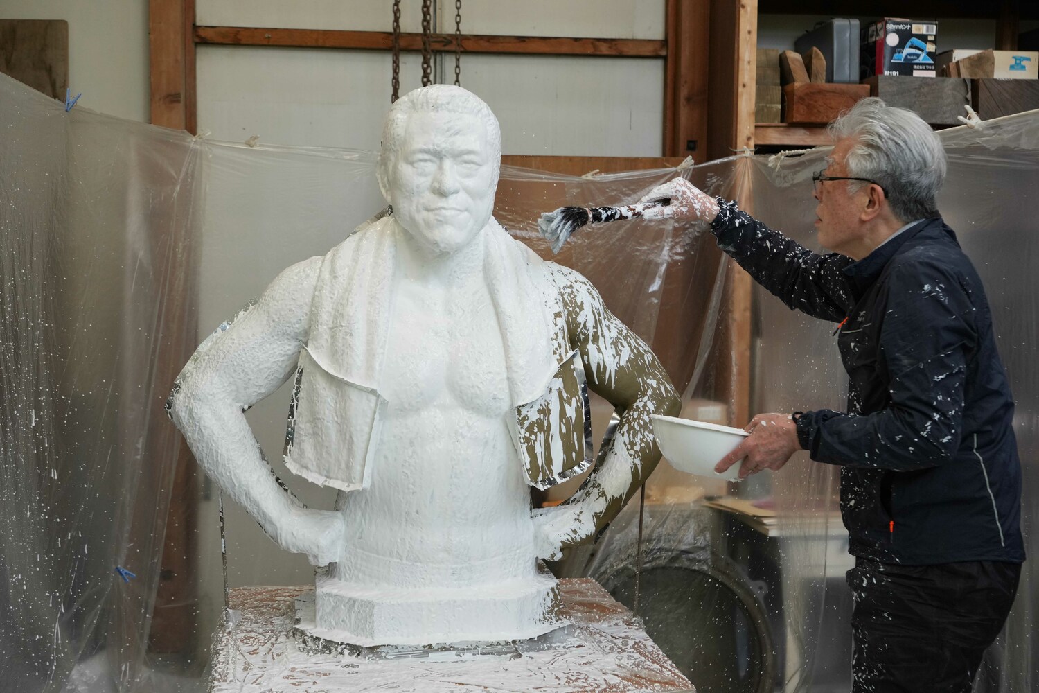 猪木像に刷毛で石膏をかけていく井野雅文さん