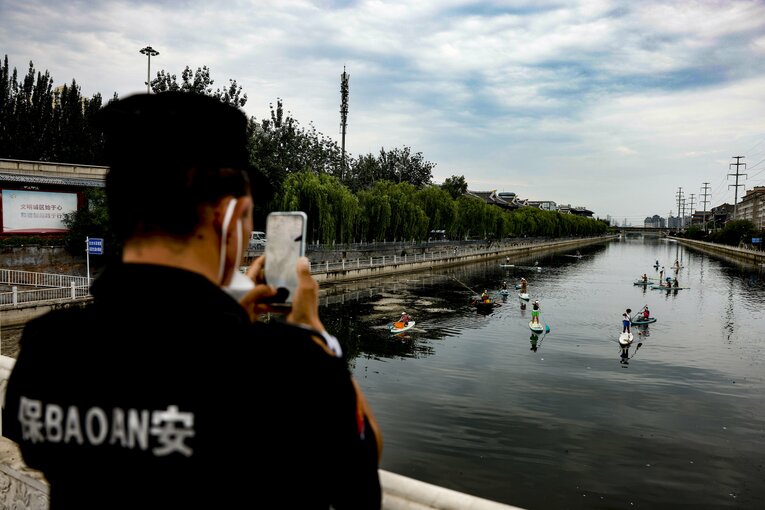 中国の北京では若者がSUPを習い、ゴミ掃除をするという流れも起きている。そしてなぜか街中を見守る保安要員がそれを撮影している　©Getty Images