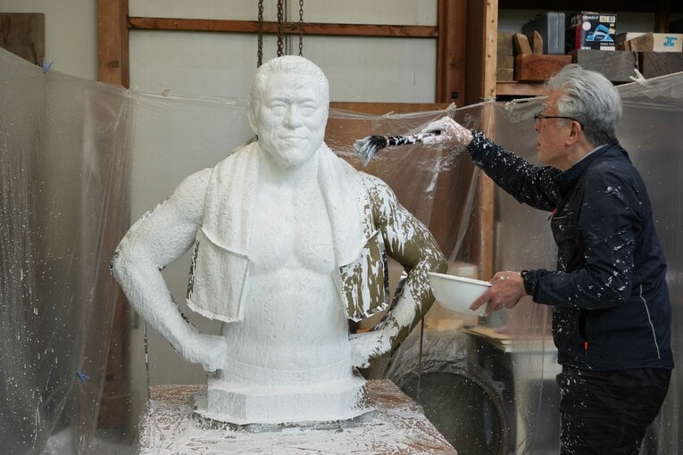 猪木像に刷毛で石膏をかけていく井野雅文さん