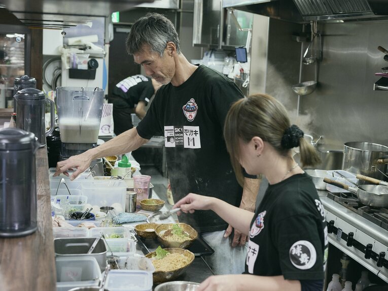 店長補佐と広報のめぐさん（右）らスタッフに支えられながら、美味しいラーメンを届ける盛田さん　©︎Yuki Suenaga