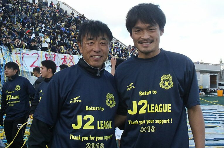 J2昇格を決め、笑顔で写真に収まる群馬・布監督（左）と渡辺。先日、布監督は松本山雅FCへの就任が発表されたが、2人の関係が途切れることはない。 ／ photograph by Takahito Ando