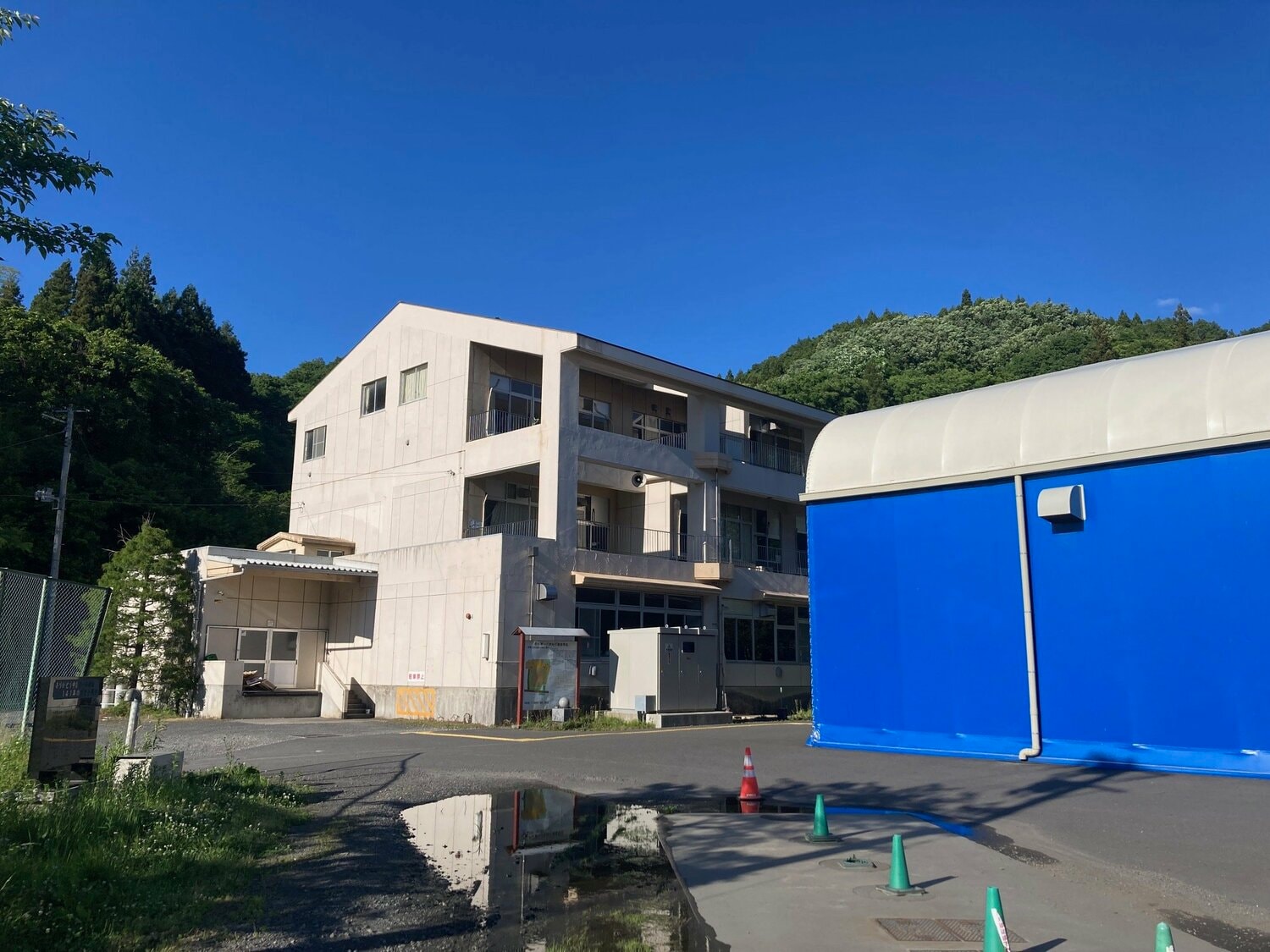 旧中谷第一小学校（写真奥）の校舎を改修して野球部寮にした。右は3年前、敷地内に完成した室内練習場