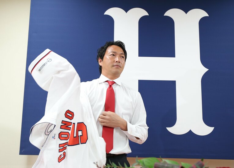 2019年1月、広島の入団記者会見。ユニフォームに袖を通す長野久義。広島から巨人にFA移籍した丸佳浩の人的補償として、巨人から移籍した　©JIJI PRESS