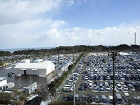 Jヴィレッジのセンターハウスからの眺め。11面あったグラウンドはアスファルトや砂利が敷かれ、駐車場などに使用されている。煙を吐き出す煙突は、火力発電所。原発事故以来、フル稼働している。