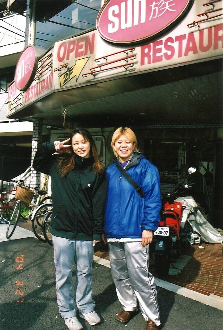 道場に寮、事務所にカフェが併設されていた自社ビルの前で、前川久美子さん（右）と　©本人提供