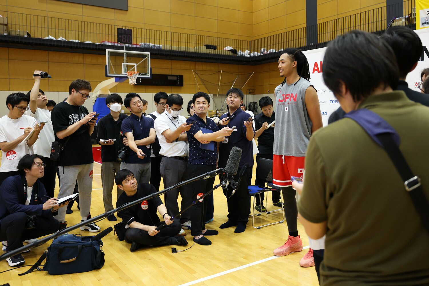 報道陣に囲まれるジェイコブス晶　©︎Takashi Aoyama/Getty Images