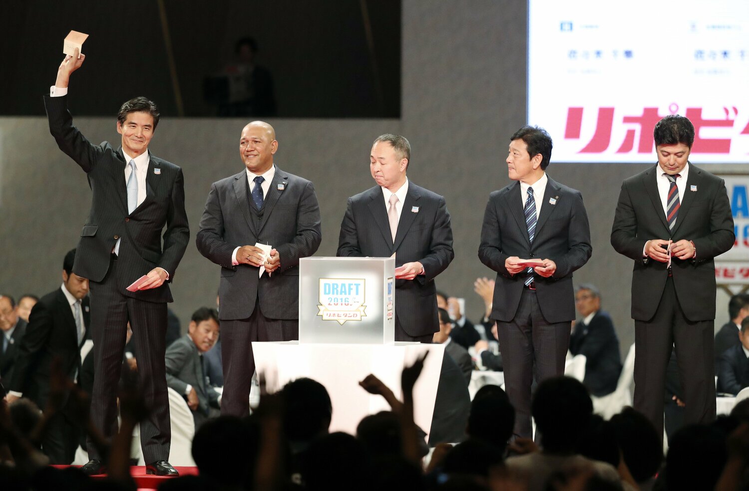 関野アナウンサーが「印象に残っている」というこのシーン。2016年ドラフトで競合したのは誰?(ヒント:左から当たりくじを掲げるロッテの山室晋也球団社長、DeNAのラミレス監督、巨人の堤辰佳GM、日本ハムの栗山英樹監督、広島の緒方孝市監督) ©JIJI PRESS