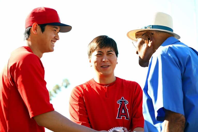 初代サイ・ヤング賞投手のドン・ニューカム（右）と握手をかわす大谷翔平。通訳も水原一平氏も　©︎Getty Images