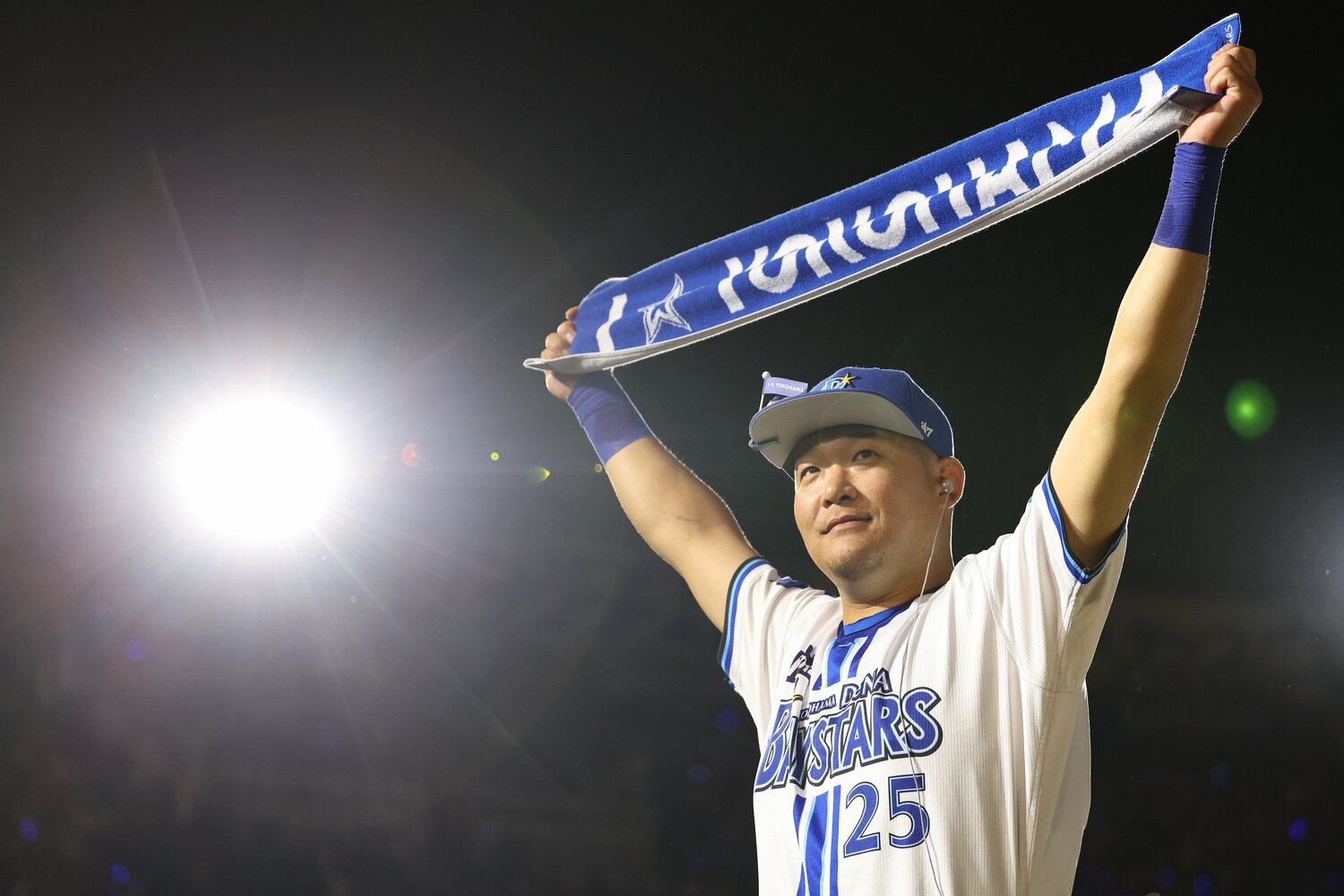 復帰戦で逆転3ランを放ち、ベイスターズのマフラーを掲げる筒香　©︎JIJI PRESS