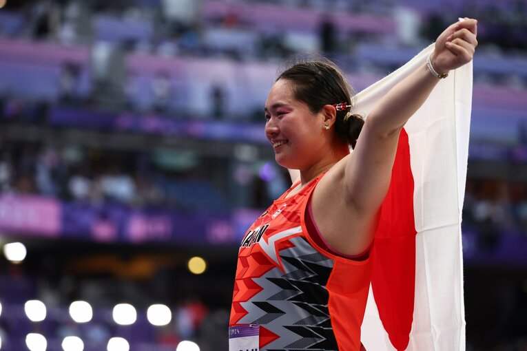 笑顔で日の丸を掲げる北口榛花　©Ryosuke Menju/JMPA