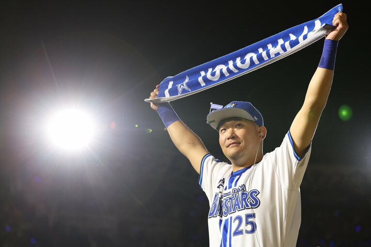 復帰戦で逆転3ランを放ち、ベイスターズのマフラーを掲げる筒香　©︎JIJI PRESS