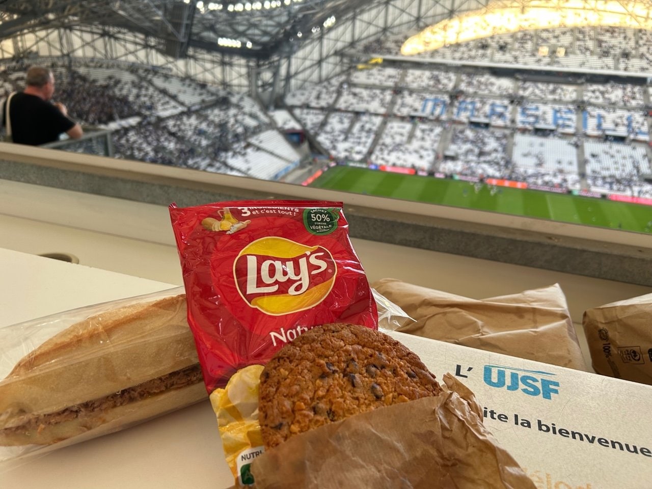 提供された「ランチ」。サンドイッチ、クッキー、ポテトチップスを記者席で頂く